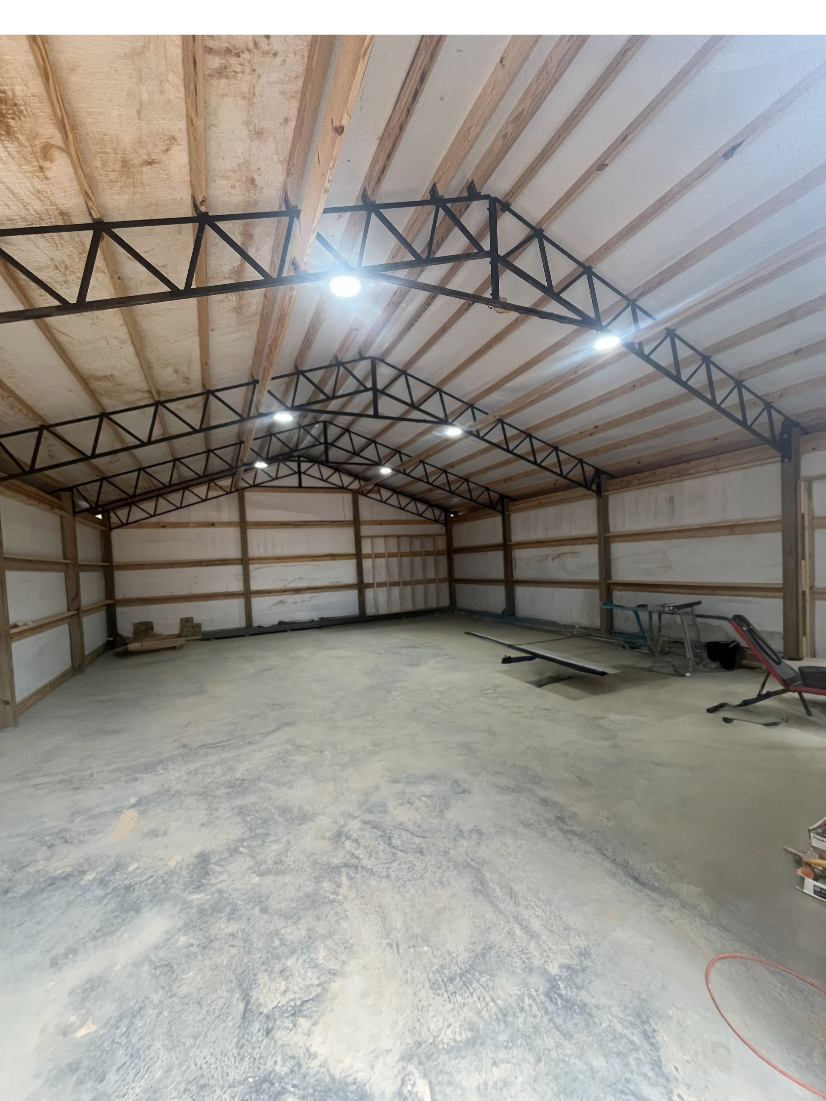 Pole barn interior showing steel trusses and spray foam insulation